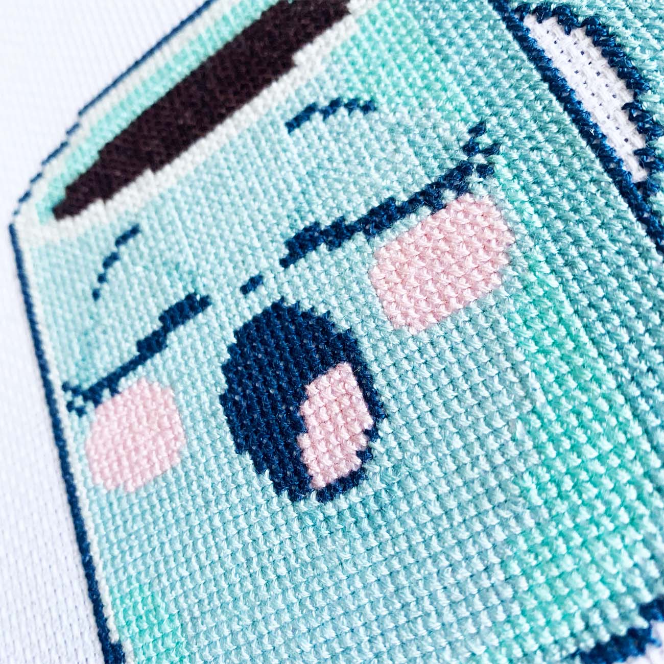 Close-up of a blue coffee mug cross stitch showing thread texture and color details.