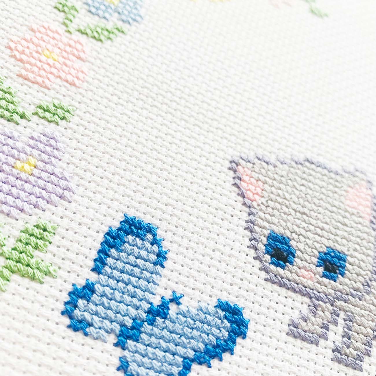 Close-up stitches of Gray Cat and butterflies cross stitch showing thread texture and color details.