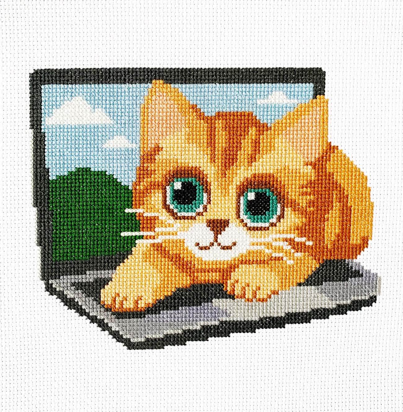 Ginger Working finished cross stitch design of an orange cat on a laptop on white Aida, showing full stitched design.