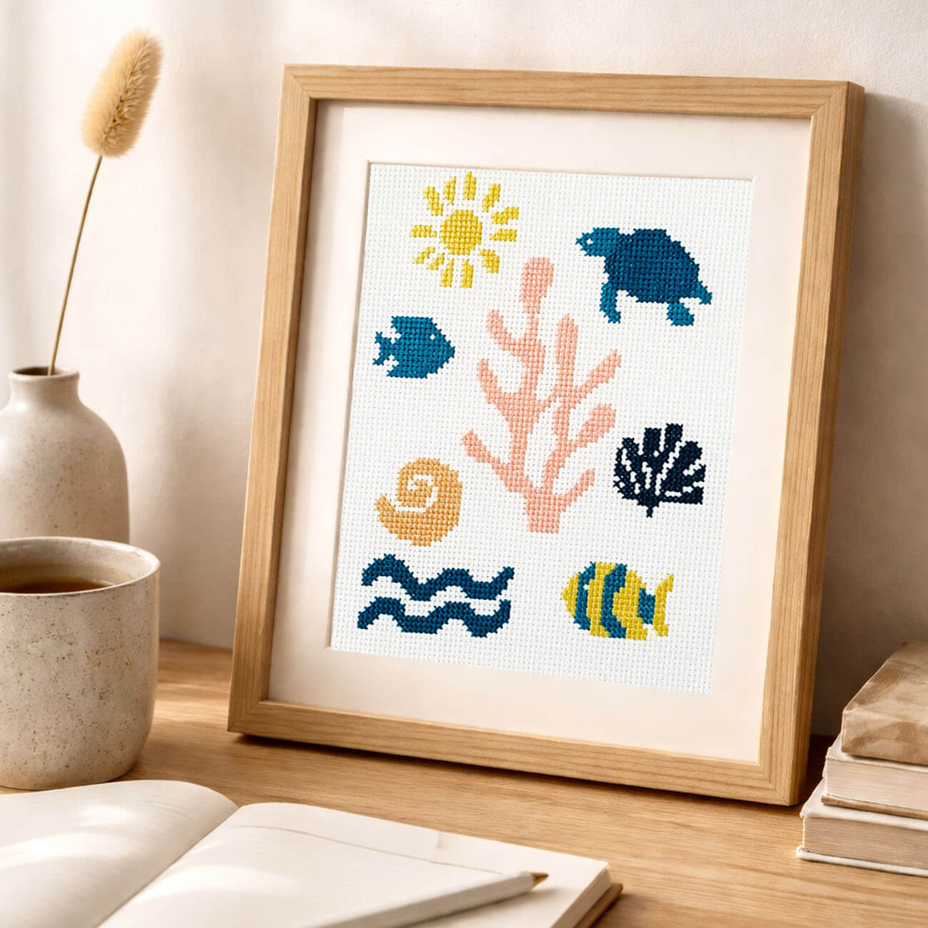 Framed cross-stitch art with ocean-themed designs on a cream fabric.