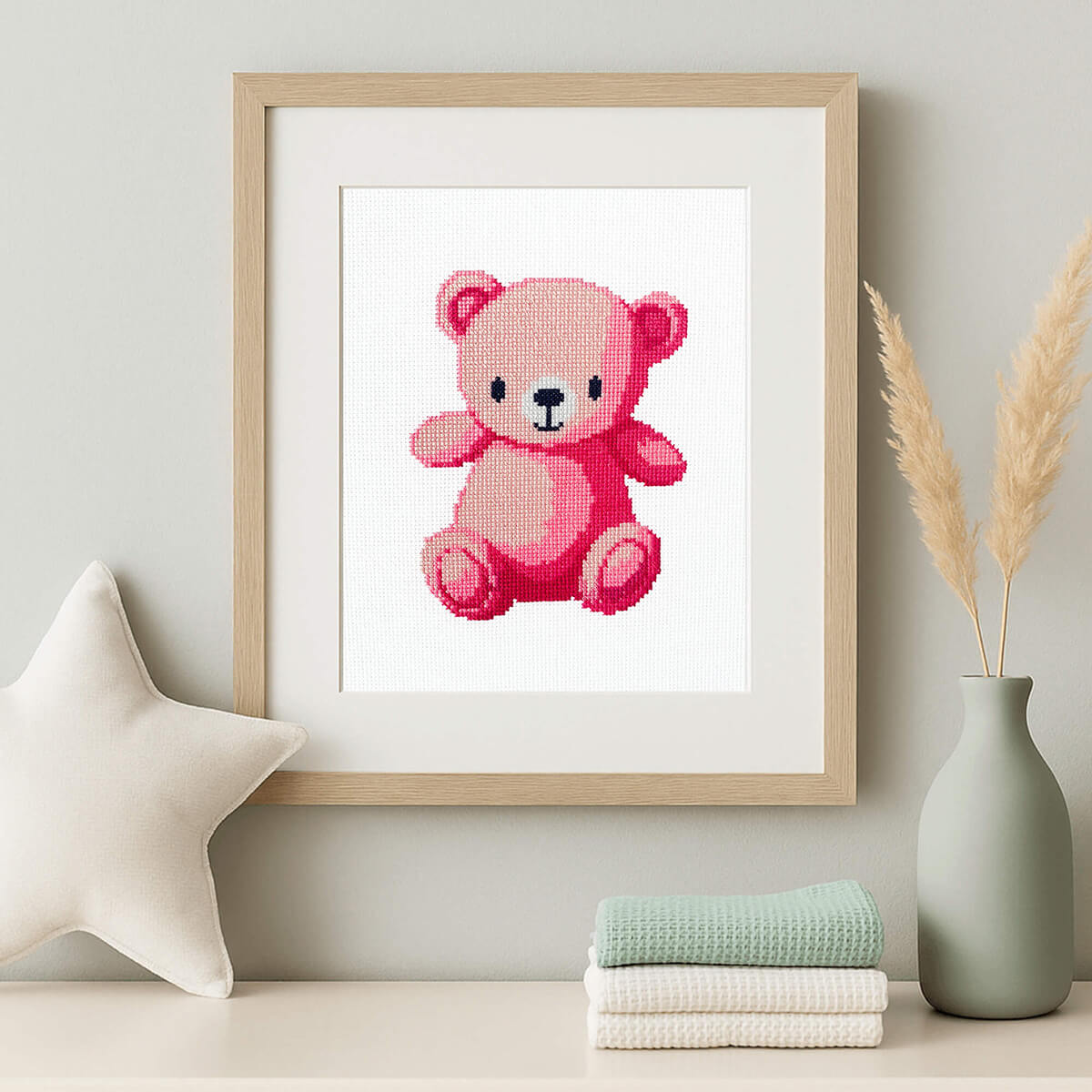 Framed cross-stitch design of a pink teddy bear.
