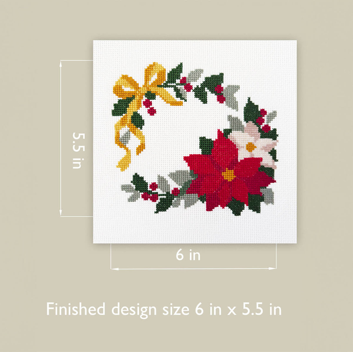 A square cross-stitch design featuring a festive wreath with red poinsettias, white flowers, green leaves, and a yellow bow, shown on a light beige background with dimension lines indicating 6 in by 5.5 in finished size.