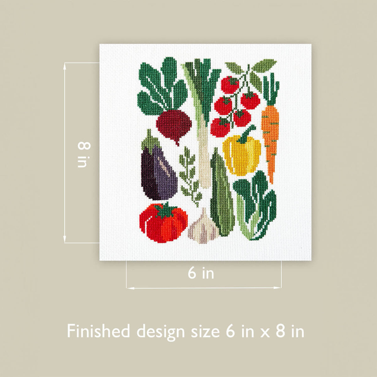 A cross-stitch design featuring colorful vegetables on a white fabric square, shown with dimension labels indicating 6 in by 8 in finished size, on a beige background.