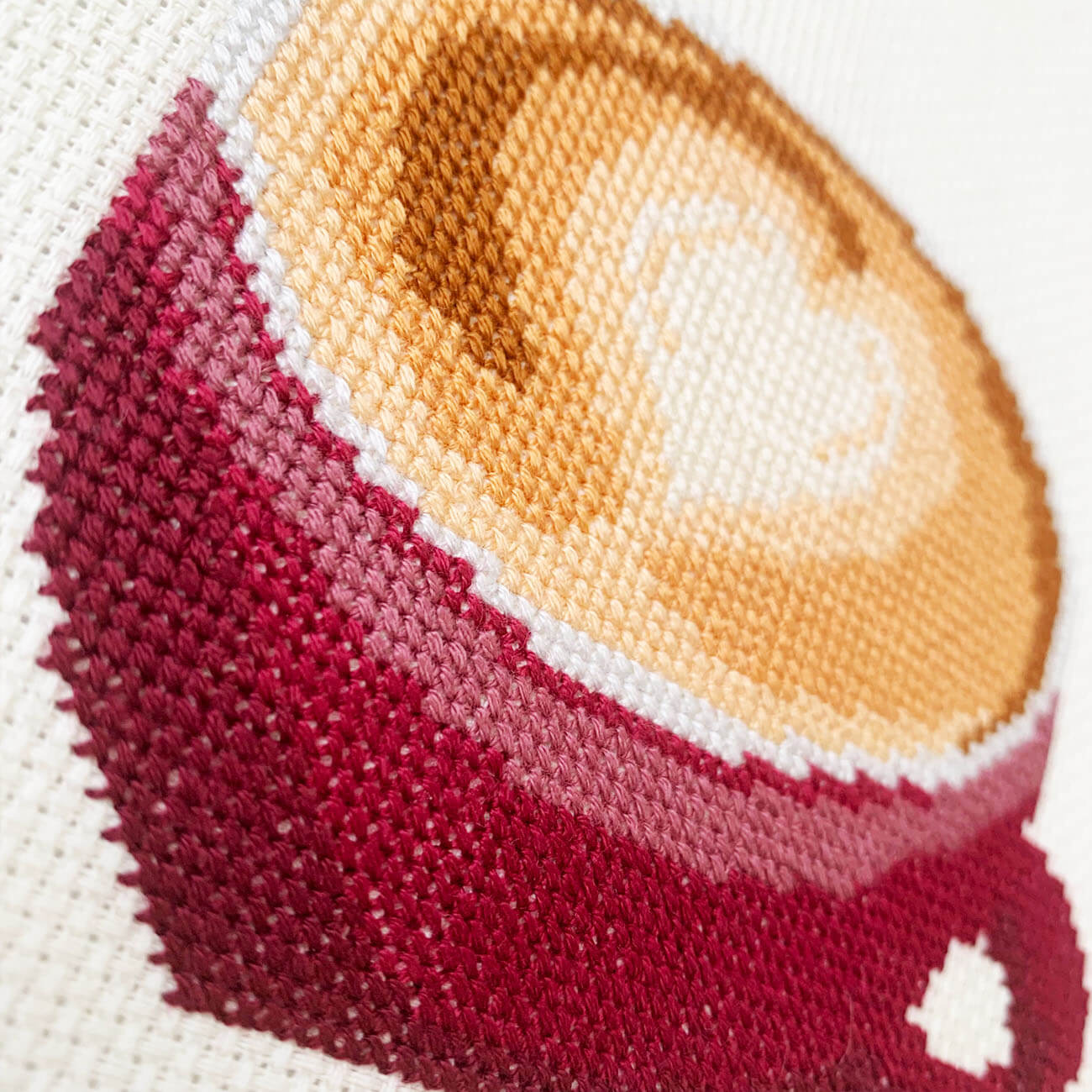 Close-up stitches of latte with heart design cross stitch showing thread texture and color details.