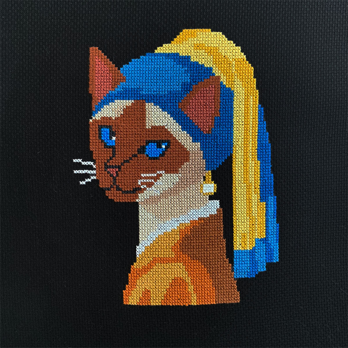 Pearl Diva Cat finished cross stitch piece on black Aida, showing full stitched design.